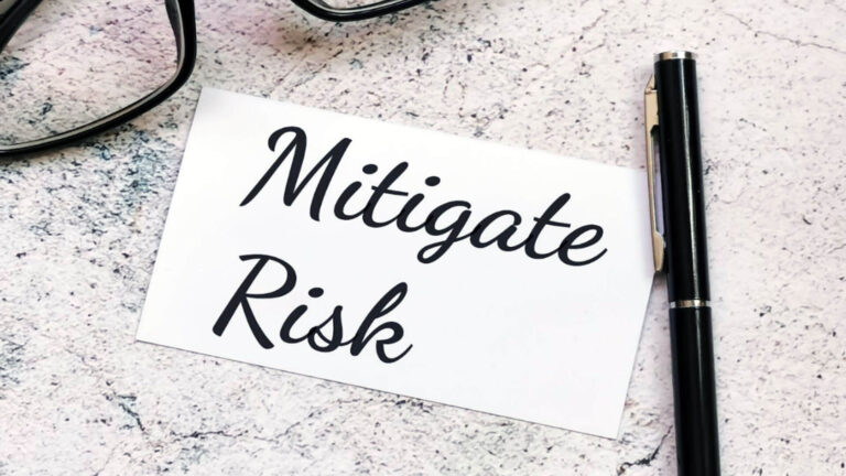 Phrase-Mitigate-Risk-written-on-paper-note-with-pen-and-eye-glasses