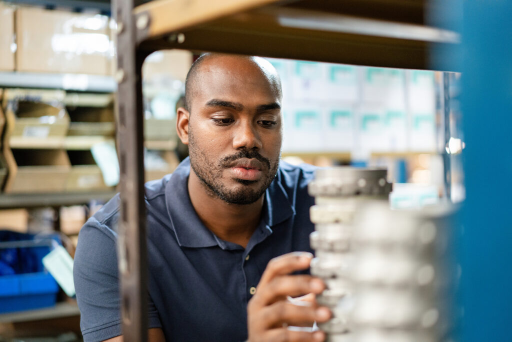 Man examines two spare parts that appear identical but are labeled with different part numbers