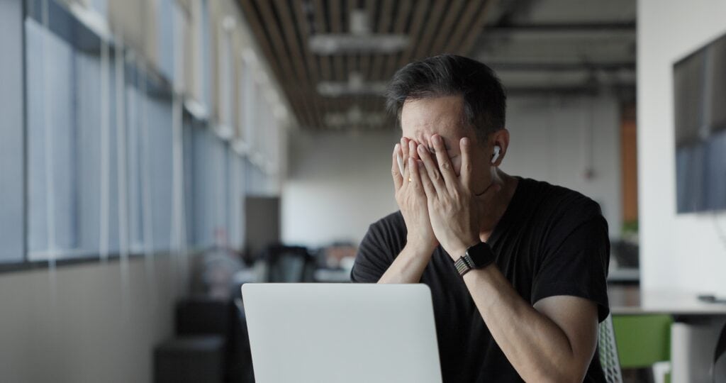 Frustrated man using a laptop with data analytics in a modern office setting.