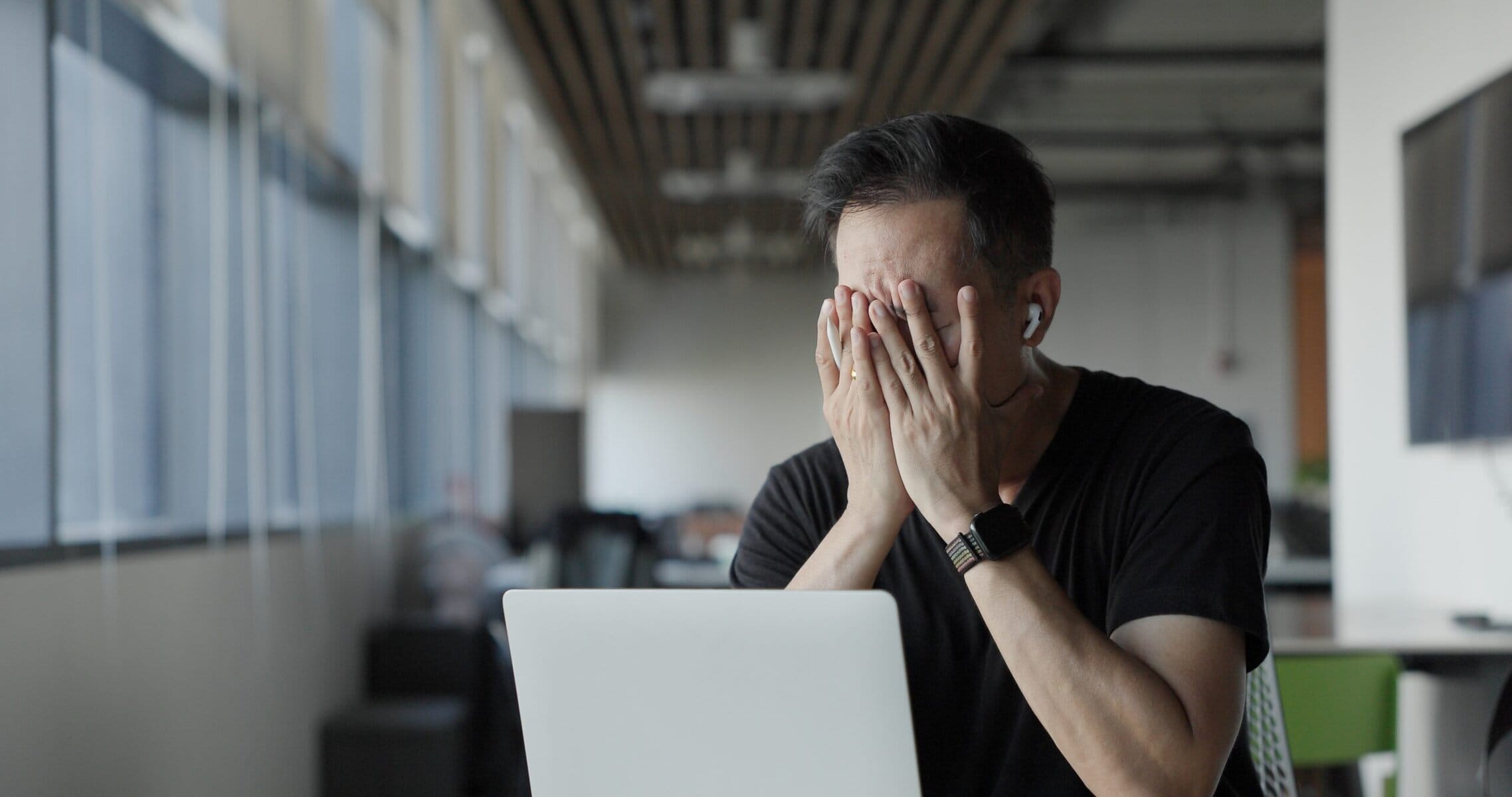 Frustrated man using a laptop with data analytics in a modern office setting.