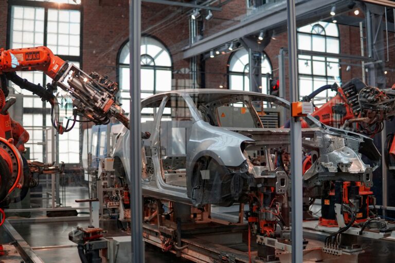 Robotic arms assembling a car in an industrial manufacturing facility.