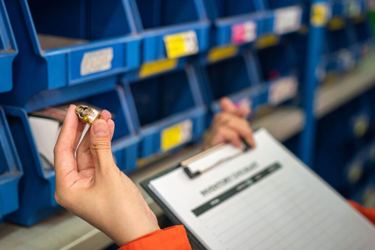 Small electronic component being held in hand in an inventory storage area.