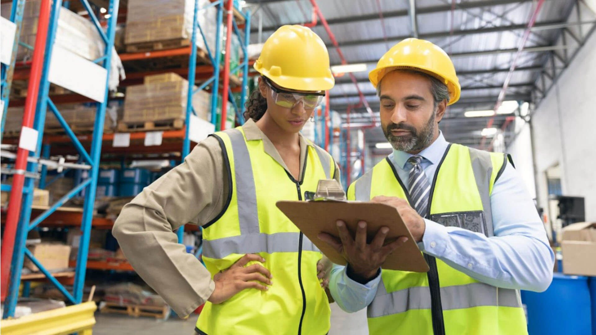 Male and female staff discussing over clipboard in warehouse Male and female staff discussing over clipboard in warehouse