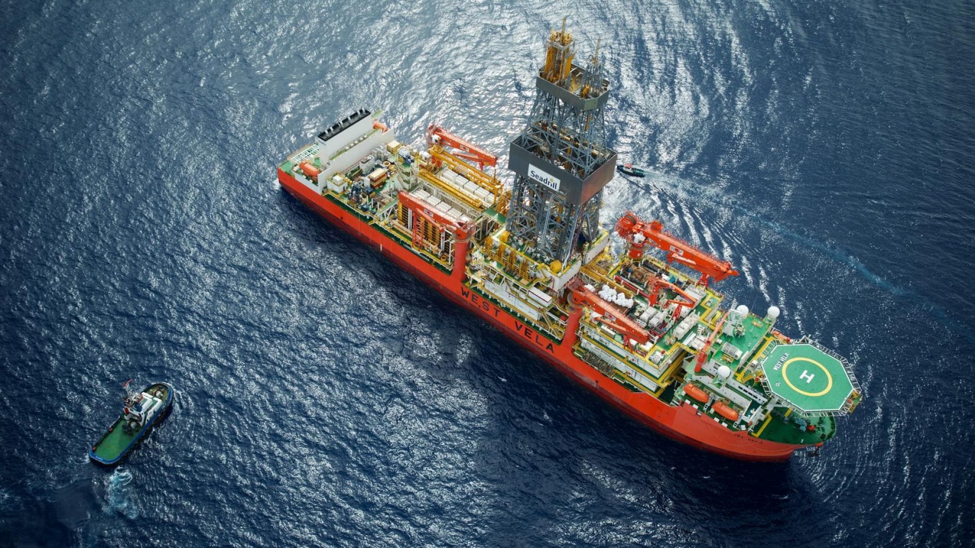 Offshore oil rig with associated supply vessel on deep blue ocean.
